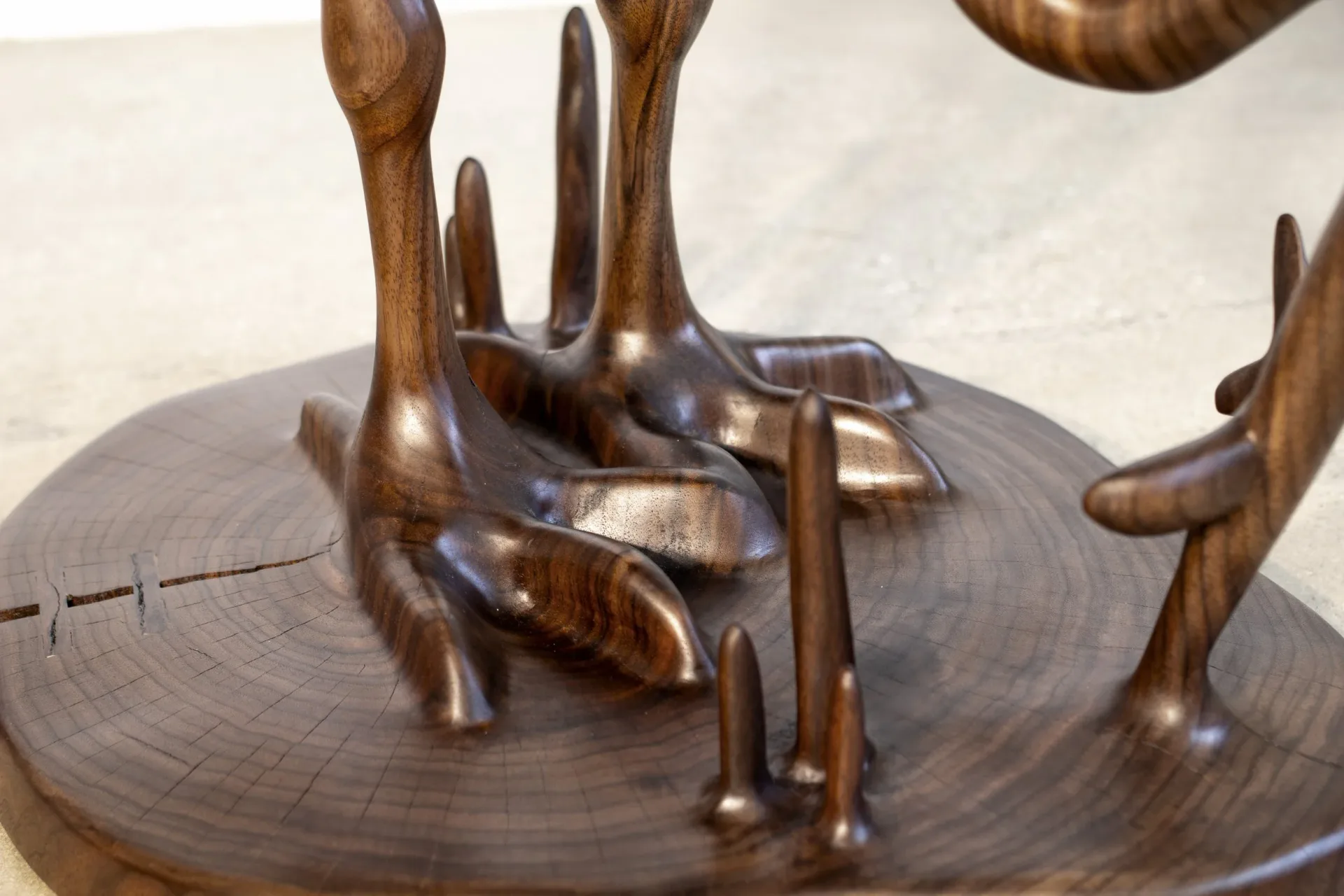 Bronze sculptural installation featuring abstracted hand forms emerging from a circular wooden base, demonstrating figurative metalwork by Aaron Poritz.