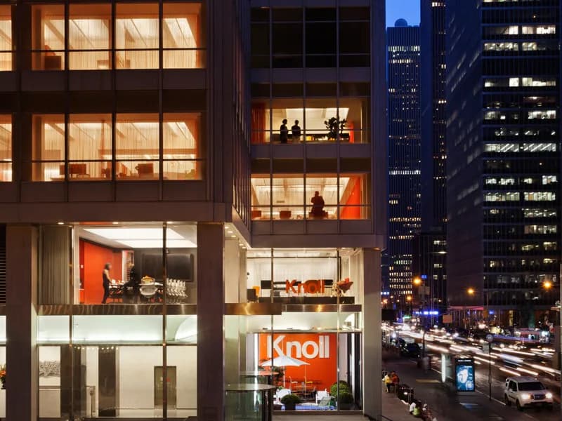 Multi-story Manhattan storefront with illuminated Knoll showroom at street level, featuring modern office and retail spaces across glass-fronted façade designed by Adam Yarinsky.