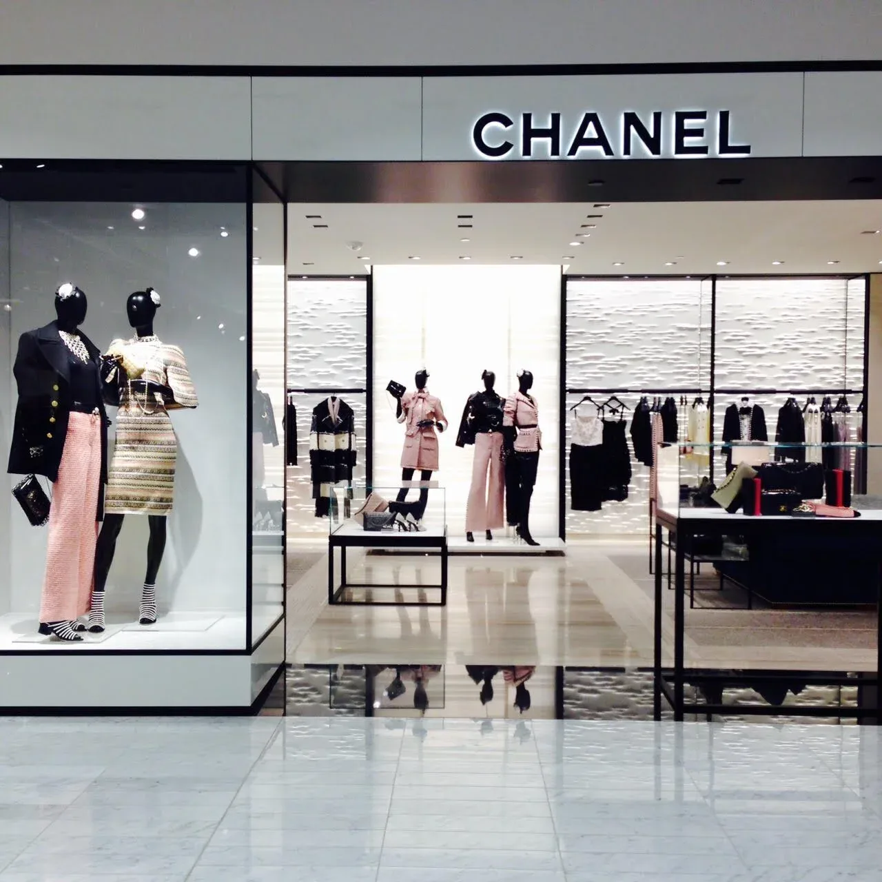 Chanel retail storefront with minimalist interior featuring black and white palette, mannequins in tailored clothing, and clean architectural lines by Agnes Liptak.