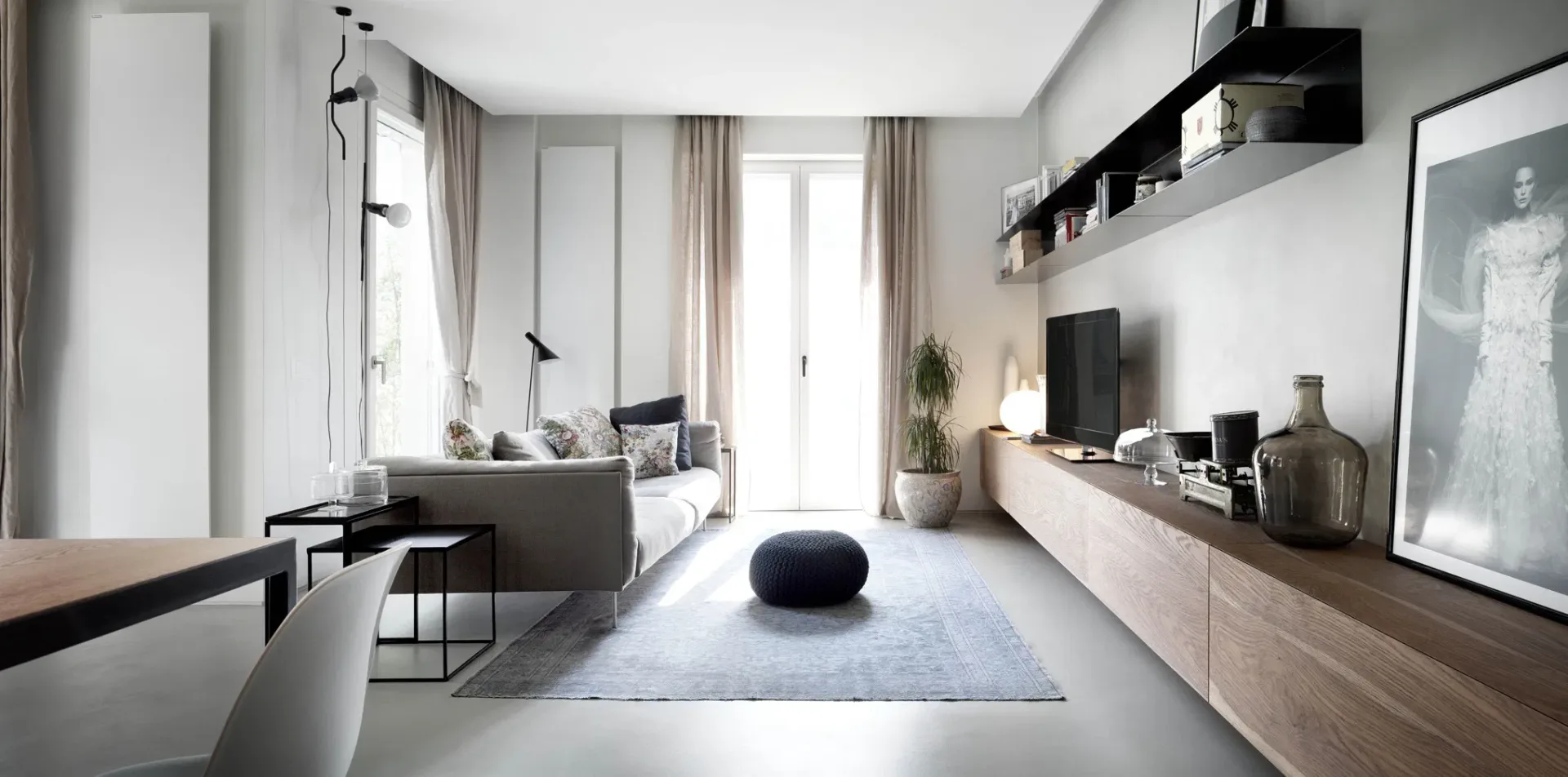 Modern studio apartment with light wood cabinetry, gray upholstered seating, and floor-to-ceiling windows, featuring crisp synthetic lighting and polished finishes by Agnieszka Wilk.