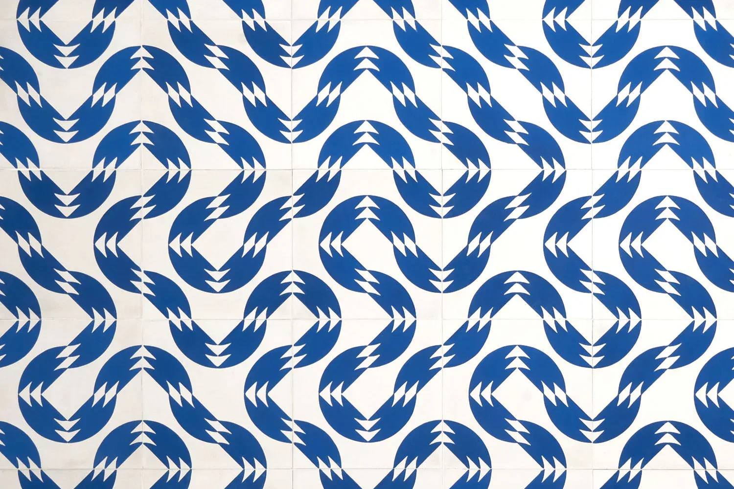 Blue and white geometric pattern featuring interlocking chevron and arrow motifs on fabric or wallcovering by Aimee Wilder.