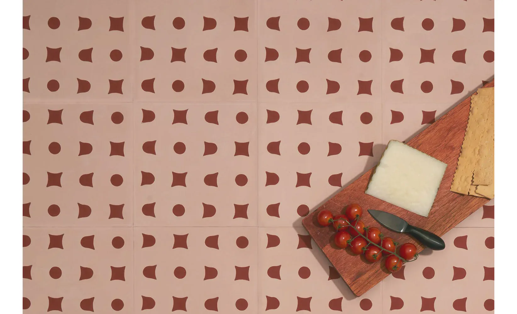 Flat-lay photograph of fabric pattern featuring a geometric repeat design in burgundy and tan tones with matching textile samples by Aimee Wilder.