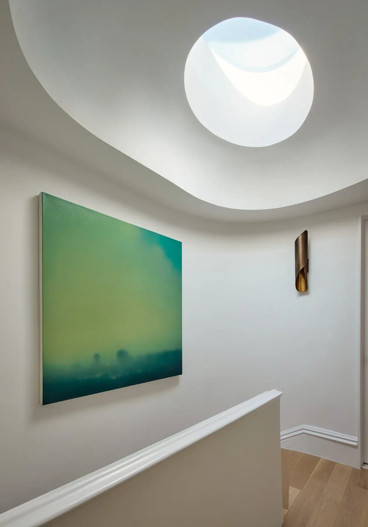 Minimalist gallery space with curved ceiling, circular skylight, green-teal gradient artwork, and wooden flooring by Alex Barker.