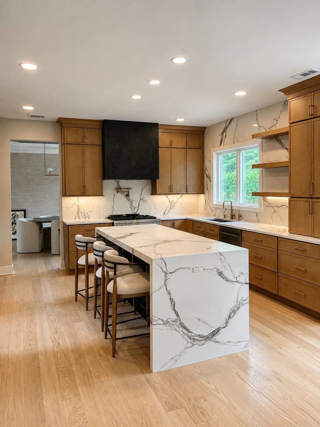 Modern kitchen interior with marble island, wood cabinetry, and stainless steel appliances, designed by Alex Hurwitz.