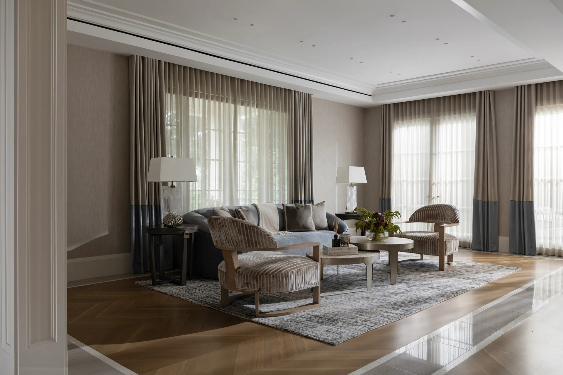 Luxurious living room with neutral taupe walls, layered drapery, upholstered seating, and polished wood flooring, designed by Aliza Katz.