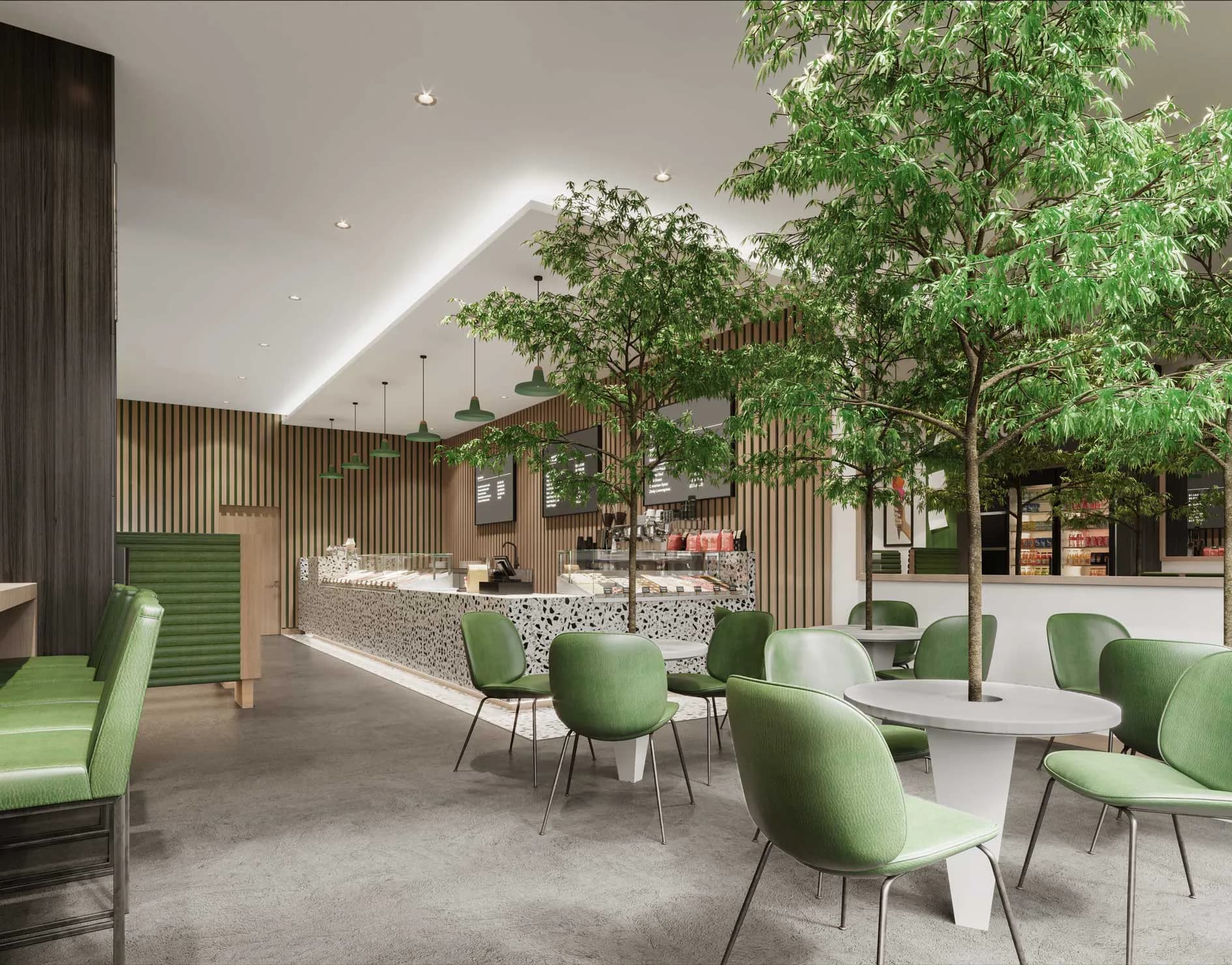 Modern café interior with green upholstered chairs, wooden slat walls, living trees, and skylight ceiling creating a biophilic workspace by Aliza Katz.