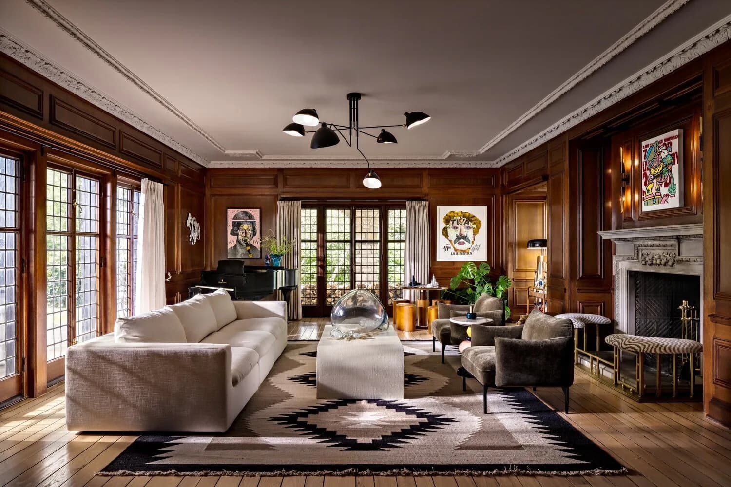 Luxurious living room with wood paneling, curved cream sofa, geometric area rug, and fireplace designed by Amy Courtney.