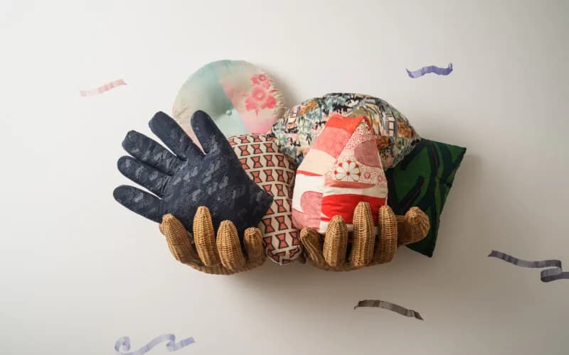 Sculptural textile and ceramic installation featuring layered fabric forms in navy, coral, and natural tones with organic wooden elements, designed by Andre Herrero.