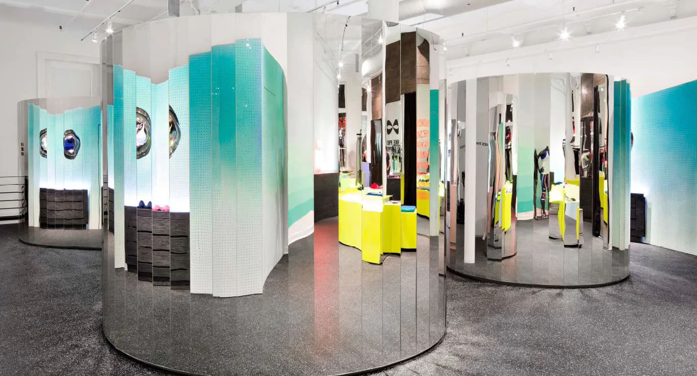 Contemporary exhibition space featuring turquoise gradient wall panels, yellow sculptural elements, and polished concrete flooring, designed by Andrew Baccon.