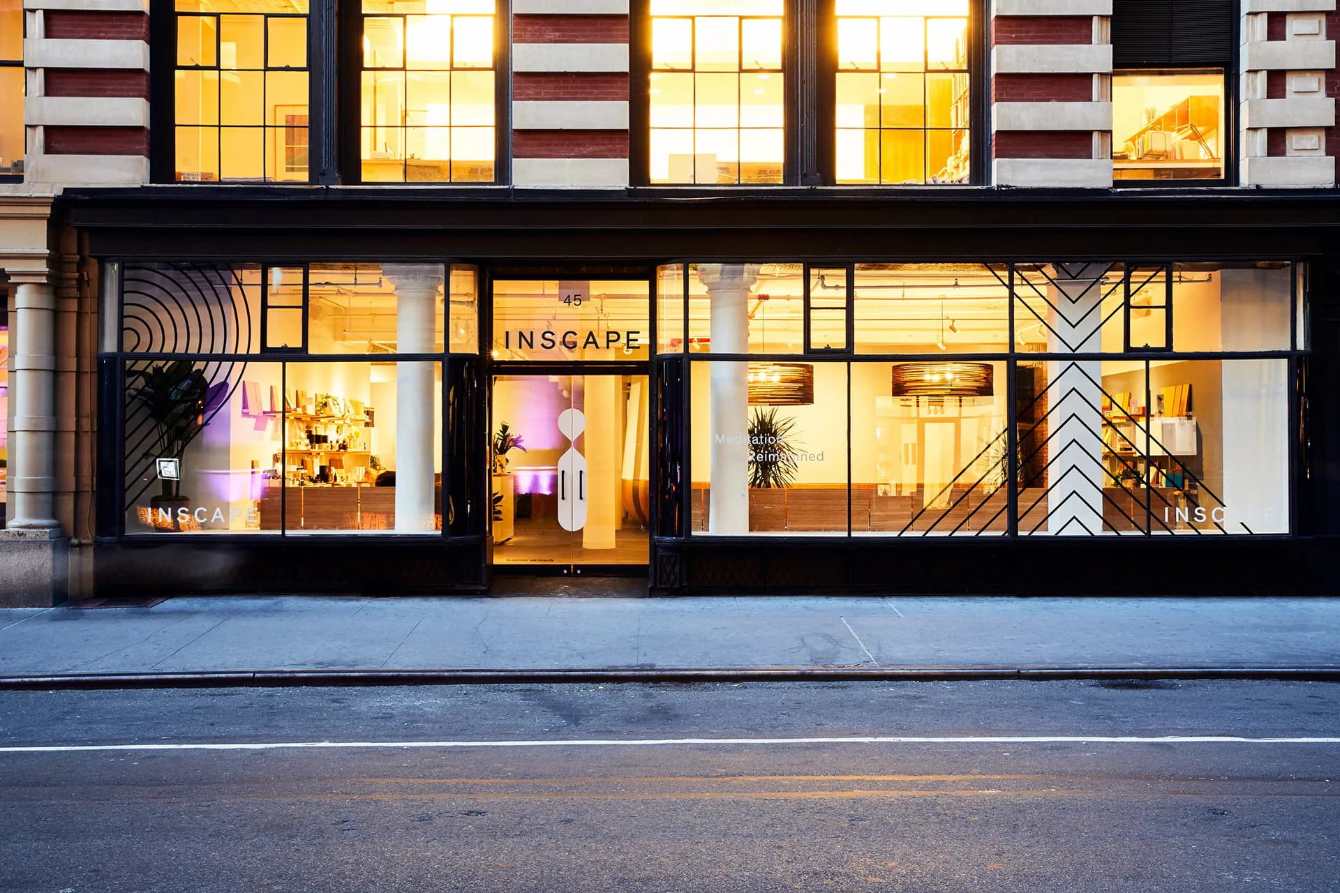 Storefront interior with warm golden lighting, modern display windows, and geometric wall detailing by Andrew Baccon.