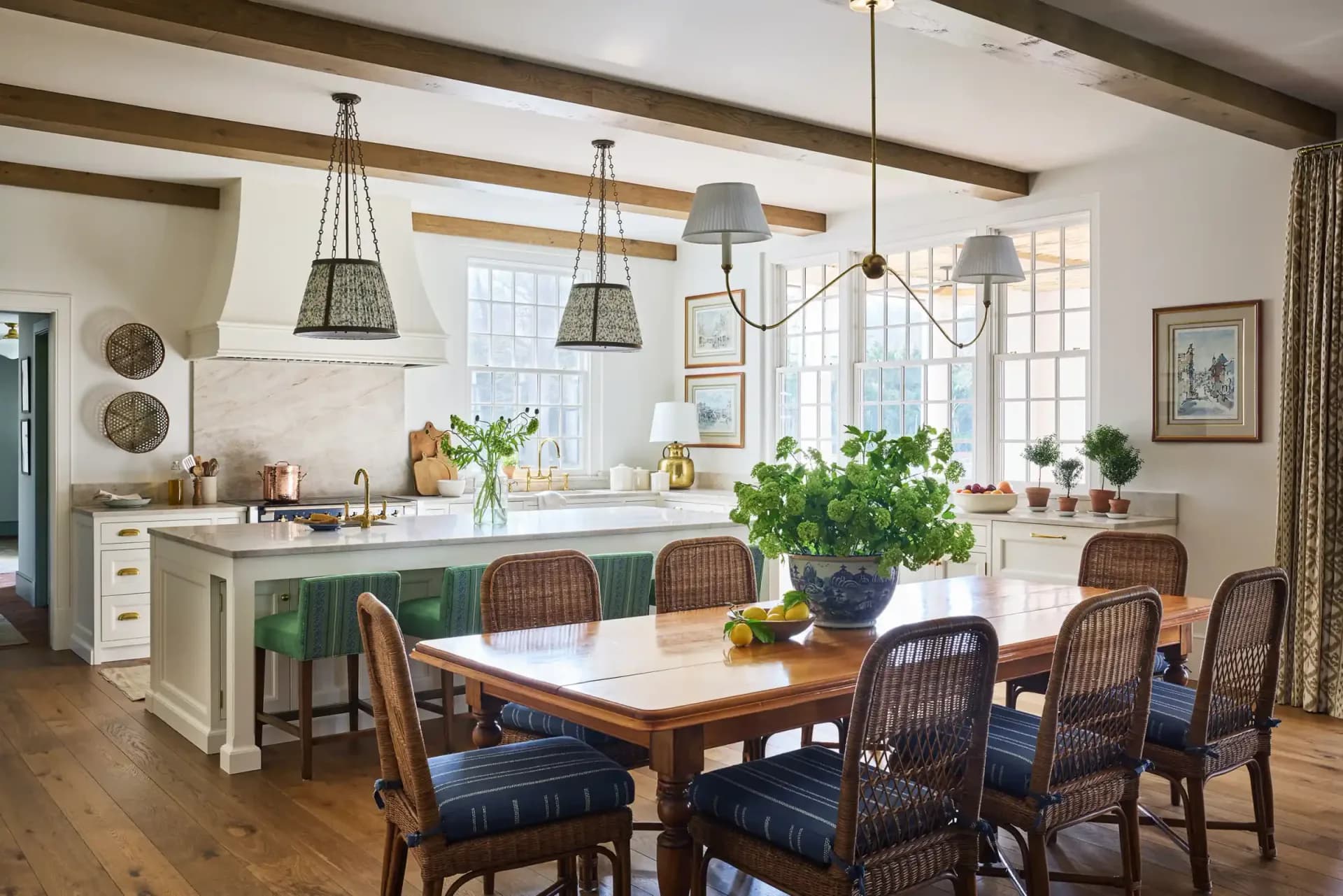 Bright kitchen and dining room with green island, wood beams, pendant lights, and woven dining chairs by Angela DeLouker.