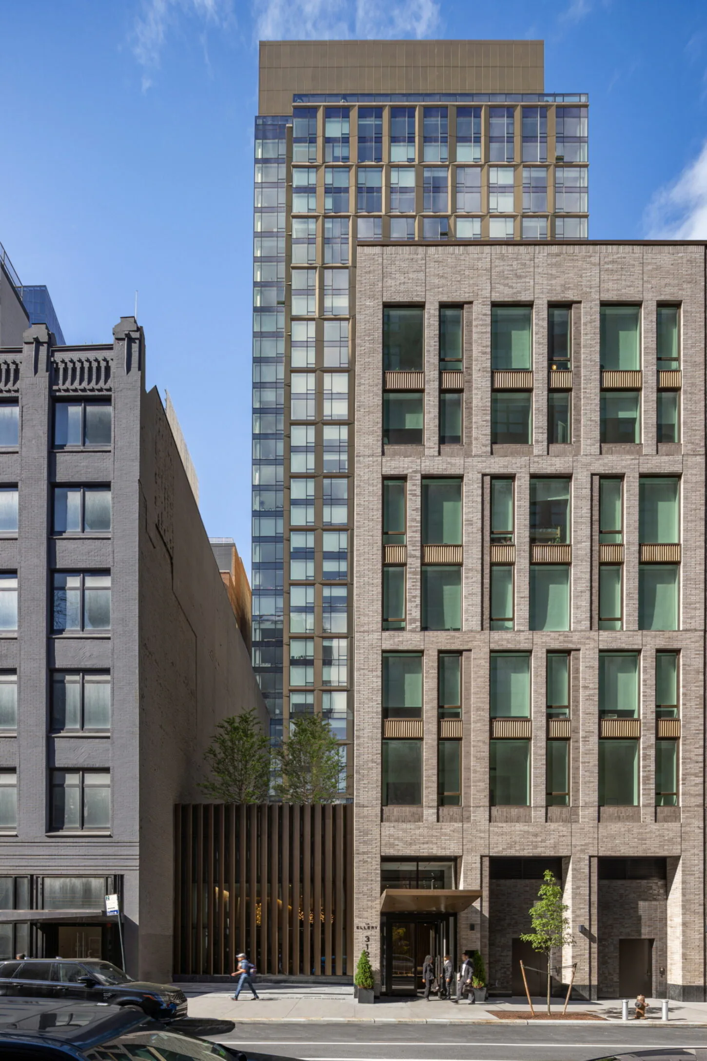Contemporary brick and glass residential tower with green-tinted windows and ground-floor retail entrance, designed by Angela Liu.
