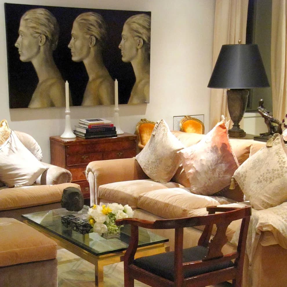 Elegant living room with beige upholstered seating, wooden coffee table, gold-toned sculptural heads artwork, and warm ambient lighting by Angelika Wrzesinska.