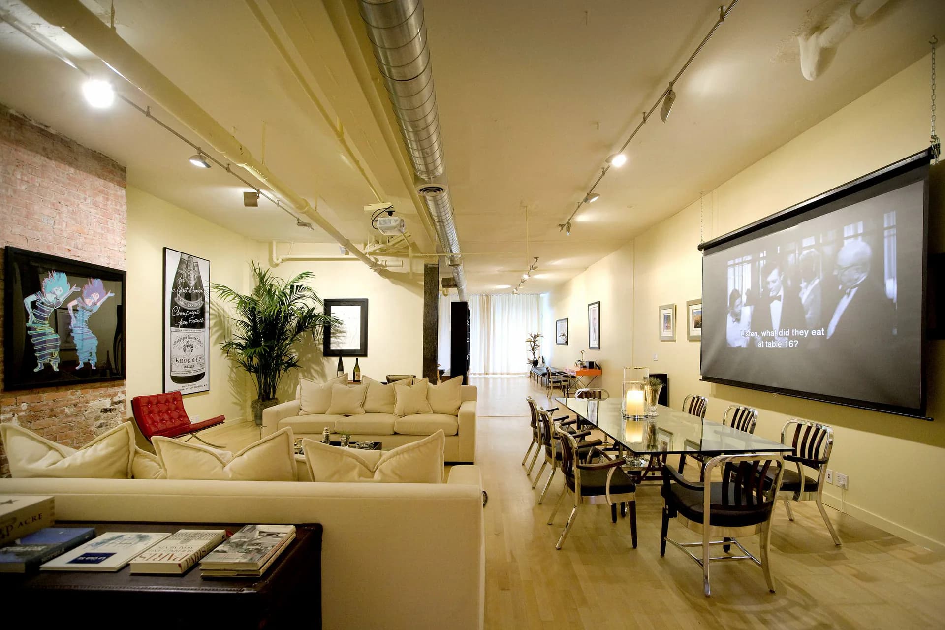 Modern gallery interior with cream-colored walls, polished concrete floor, and track lighting displaying artwork and a projection screen, designed by Angelika Wrzesinska.