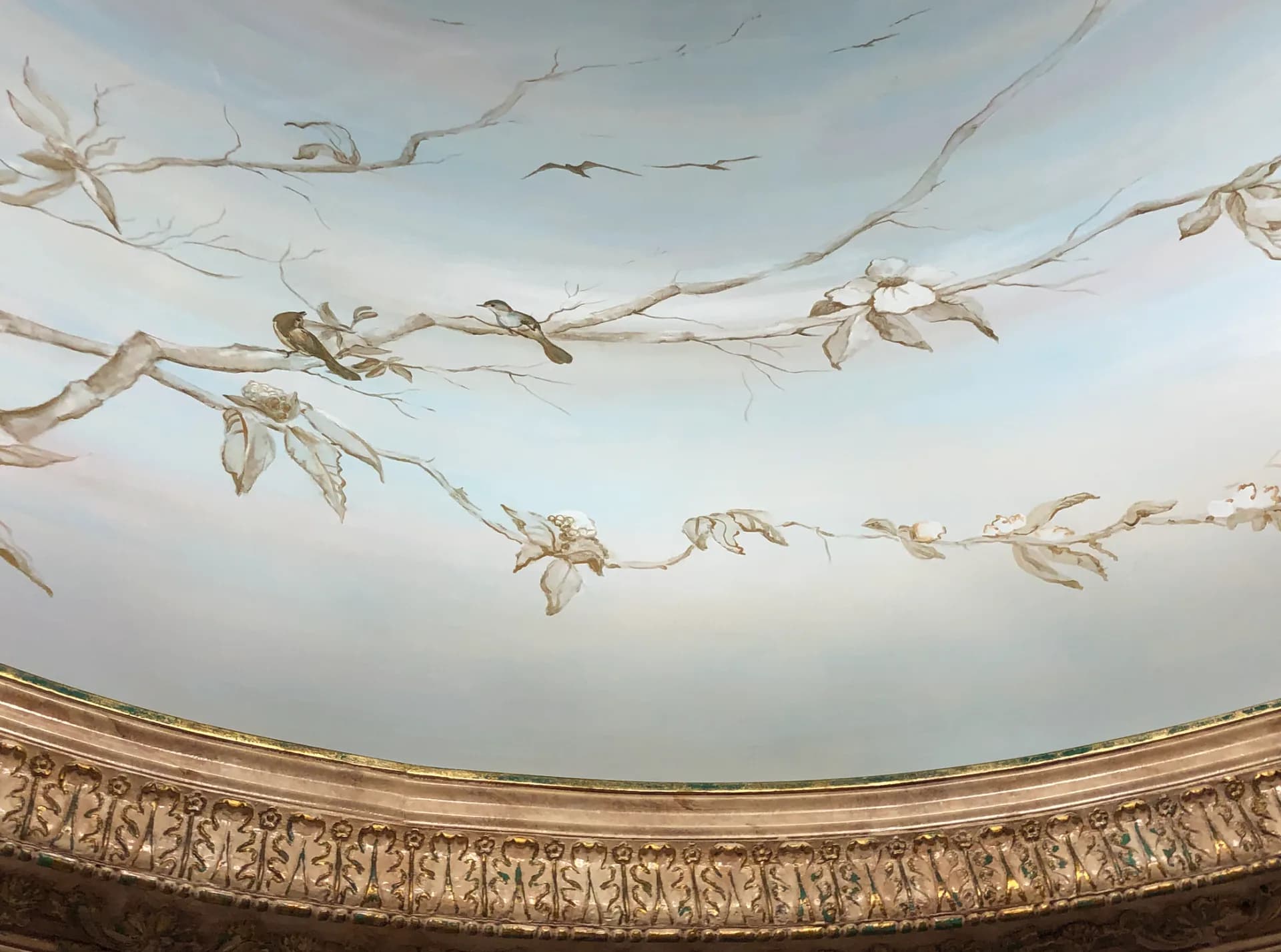 Ornate ceiling dome with decorative plasterwork and delicate botanical garland installations suspended across the curved architectural surface by Ani Brieger.