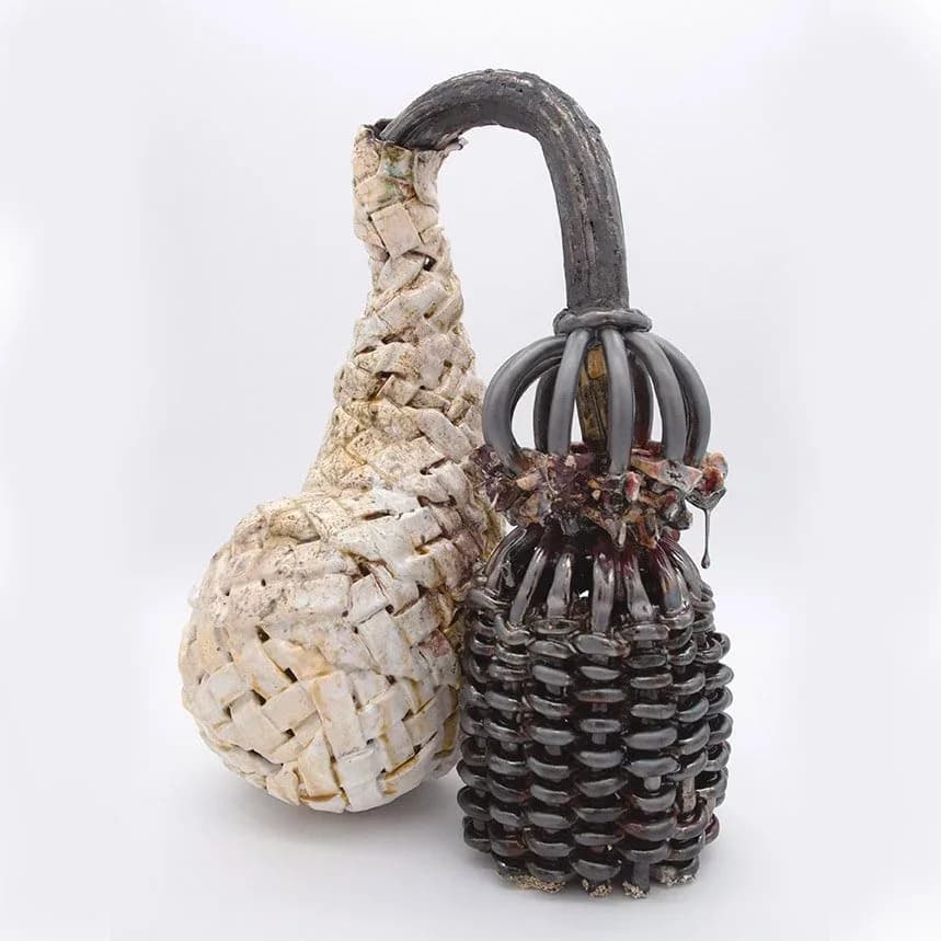 Two woven basket vessels with curved handles in natural straw and dark woven materials, crafted by Anina Major.