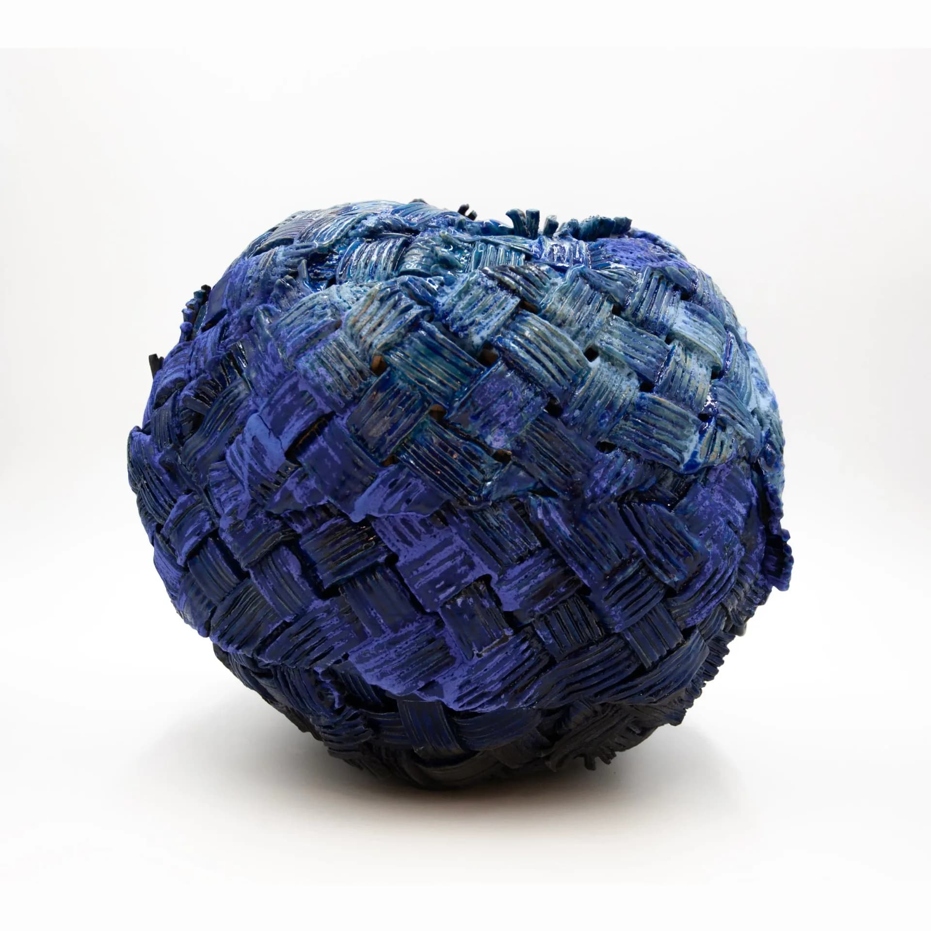 A spherical sculptural form with textured surface in deep blue and black tones, featuring layered geometric patterns, by Anina Major.