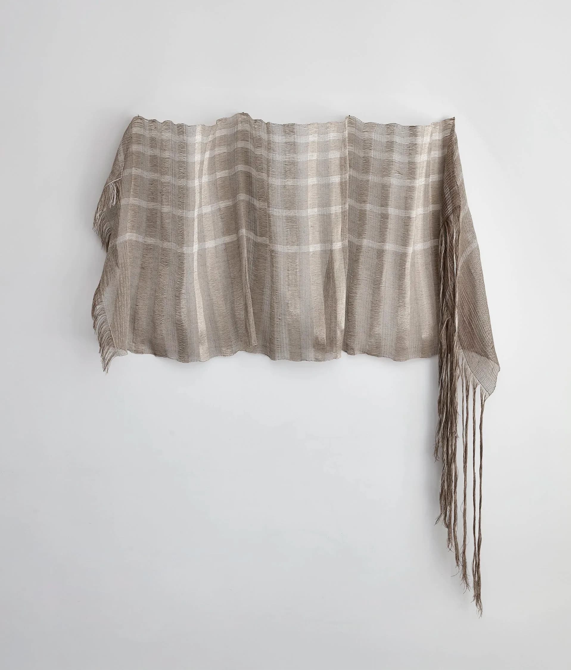 Draped linen textile with vertical pleated panels and fringe detailing in neutral beige tones by Anjuli Bernstein.