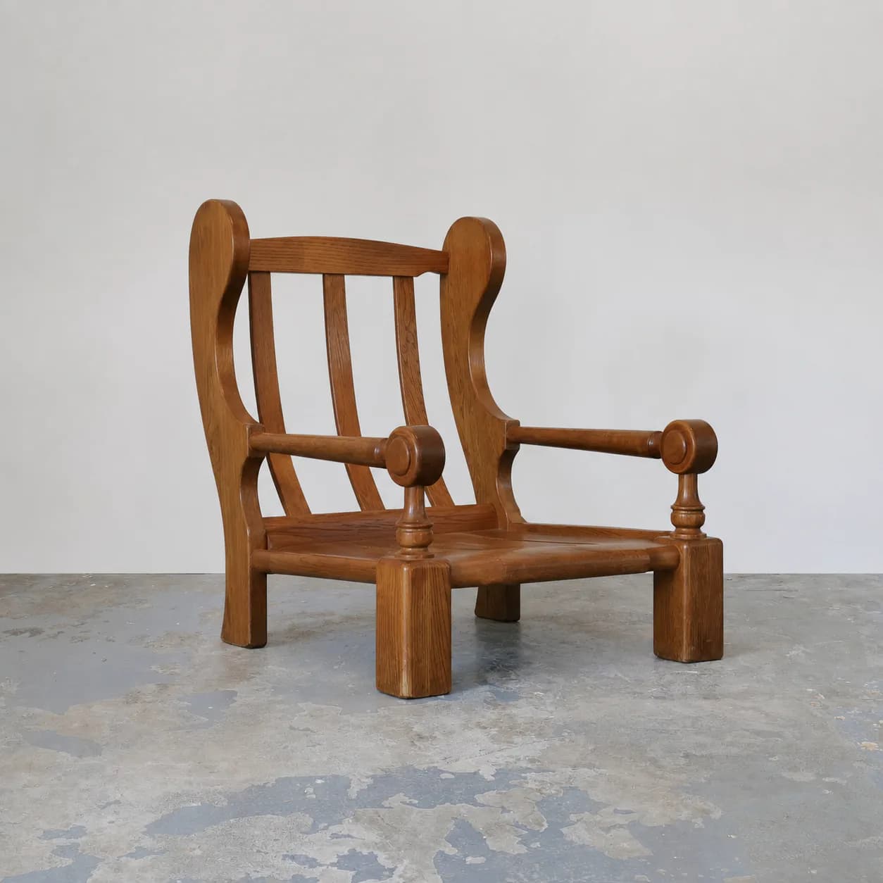 Sculptural wooden armchair with curved backrest and turned details in warm brown tone, photographed against neutral background by Antony Todd.