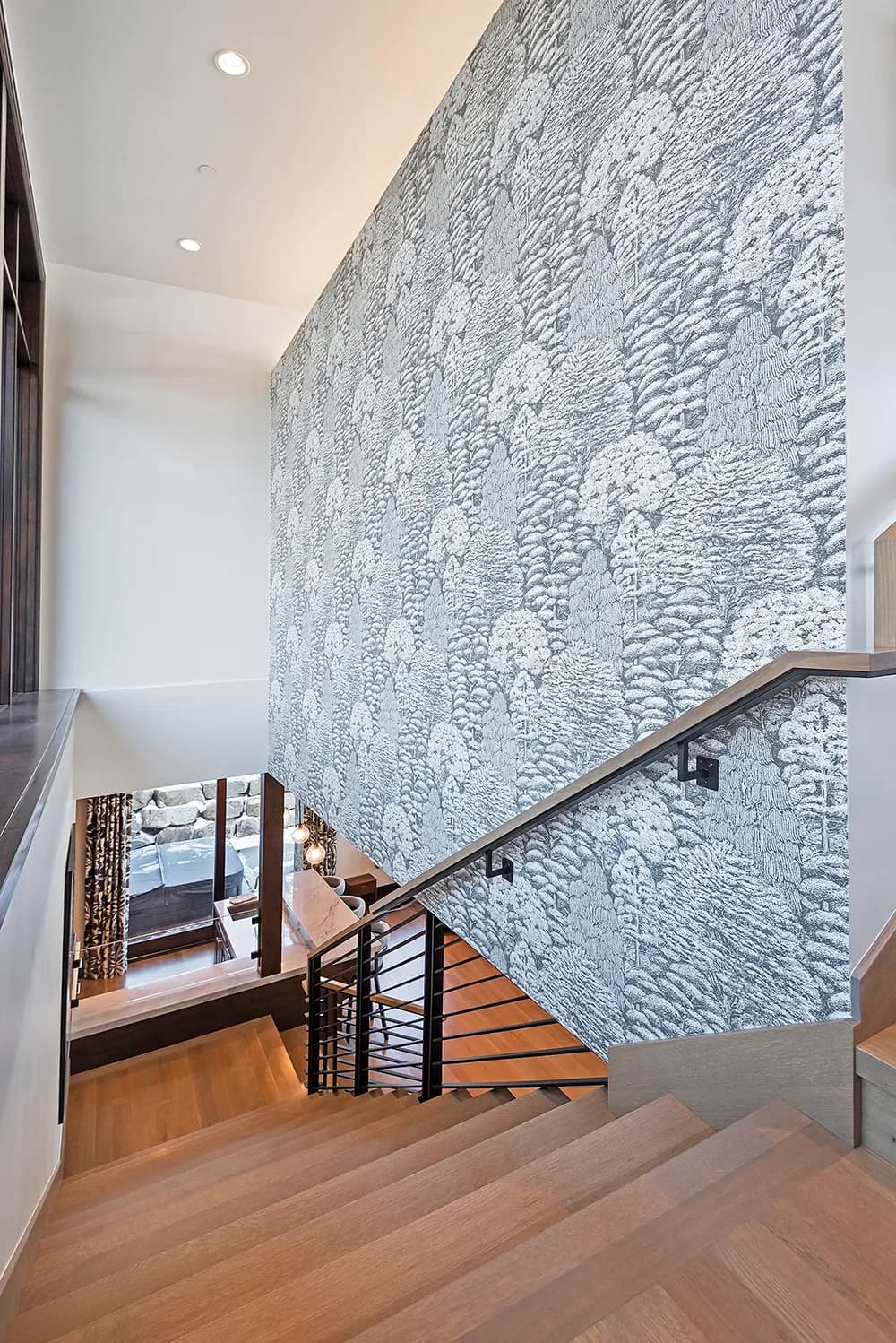 Modern stairwell with textured white brick wall, wooden treads, metal railing, and recessed lighting by Arlene Reilly.