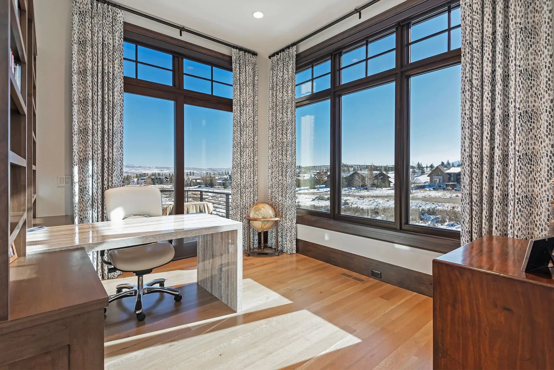 Modern high-rise office with floor-to-ceiling windows, wooden desks, hardwood flooring, and city skyline views, designed by Arlene Reilly.