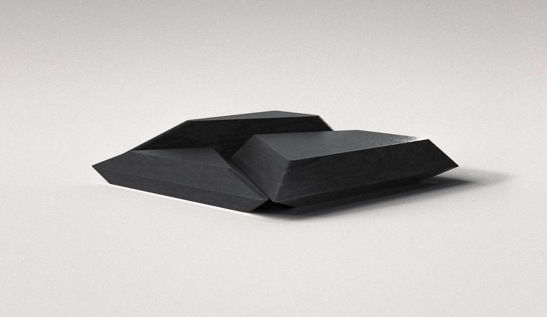 Abstract black geometric forms with folded planes and sharp angles arranged on a neutral surface by Arthur Vallin.