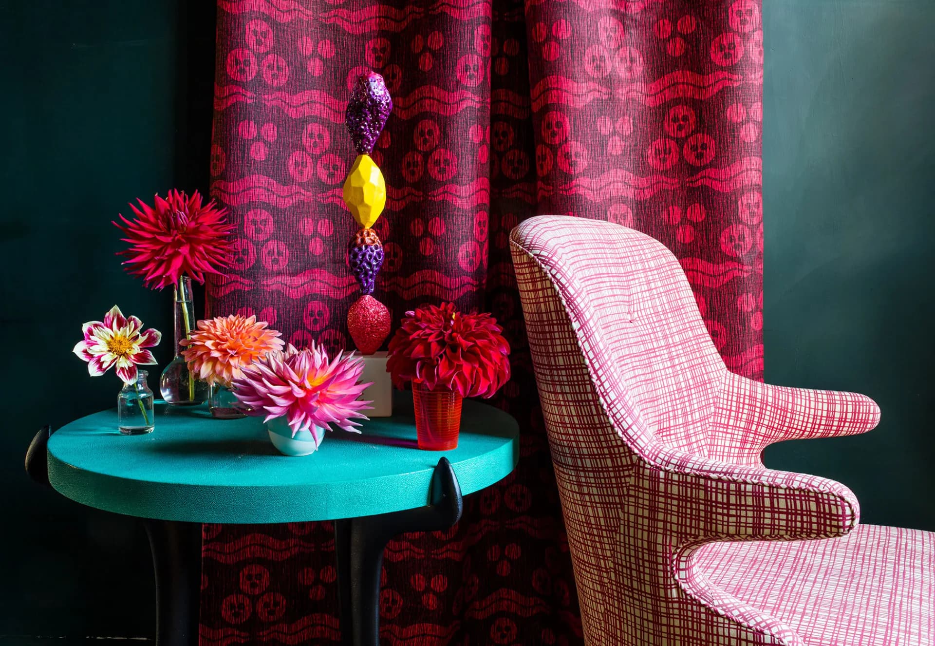 Jewel-toned interior with turquoise round table, pink patterned chair, magenta damask curtains, and fresh flowers by Ashley Hicks.
