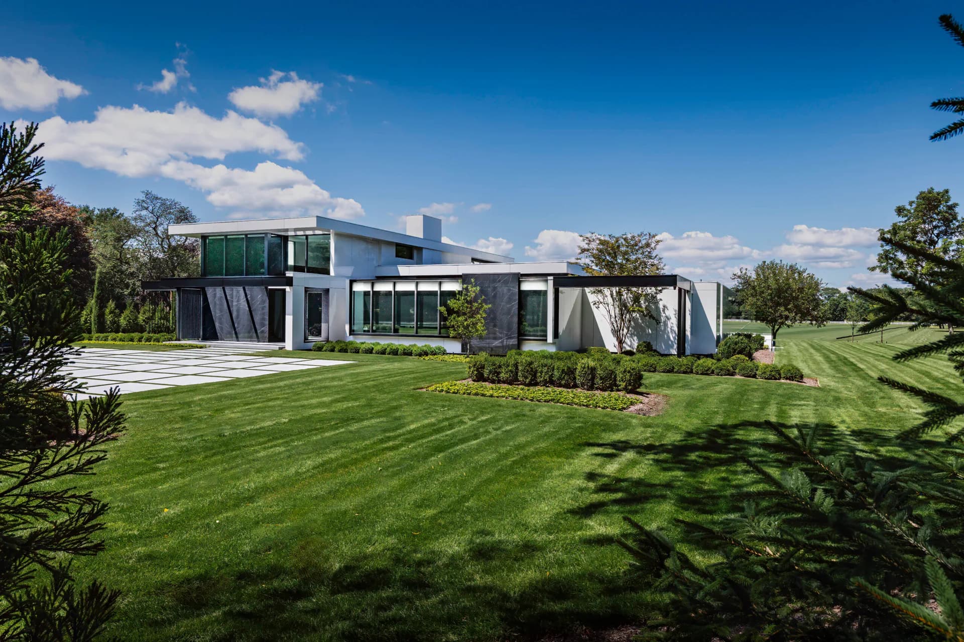 Modern residential architecture with clean geometric lines, green-toned exterior cladding, and expansive manicured lawn by Ashley Rose Walsh.