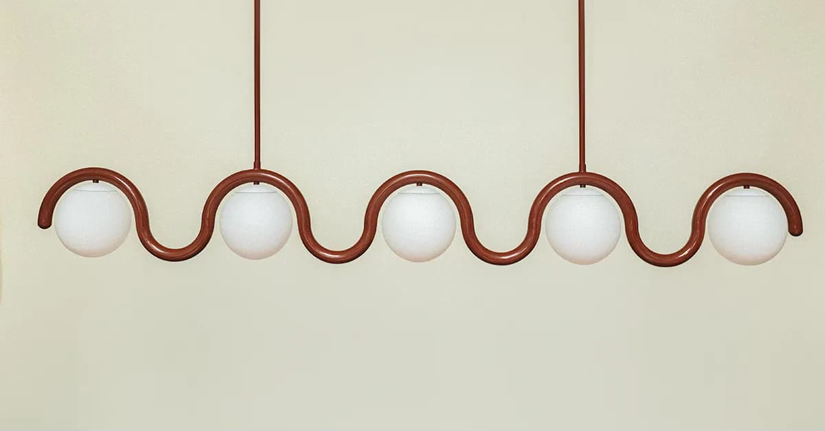 Undulating bronze pendant light fixture with five white glass spheres suspended by curved metalwork, creating a wave-like composition by Astraeus Clarke.