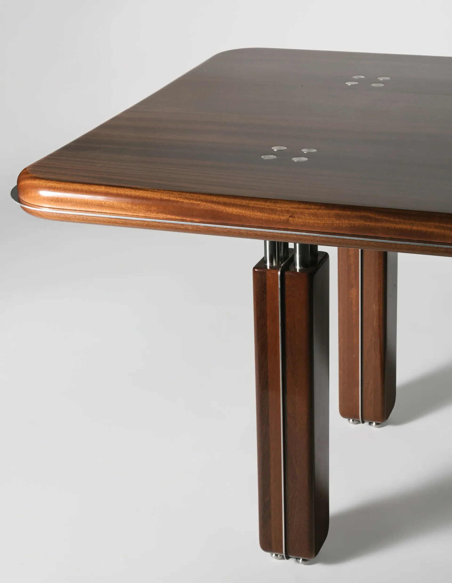 Contemporary wooden dining table with rounded edges and tapered legs in warm walnut finish by Astraeus Clarke.