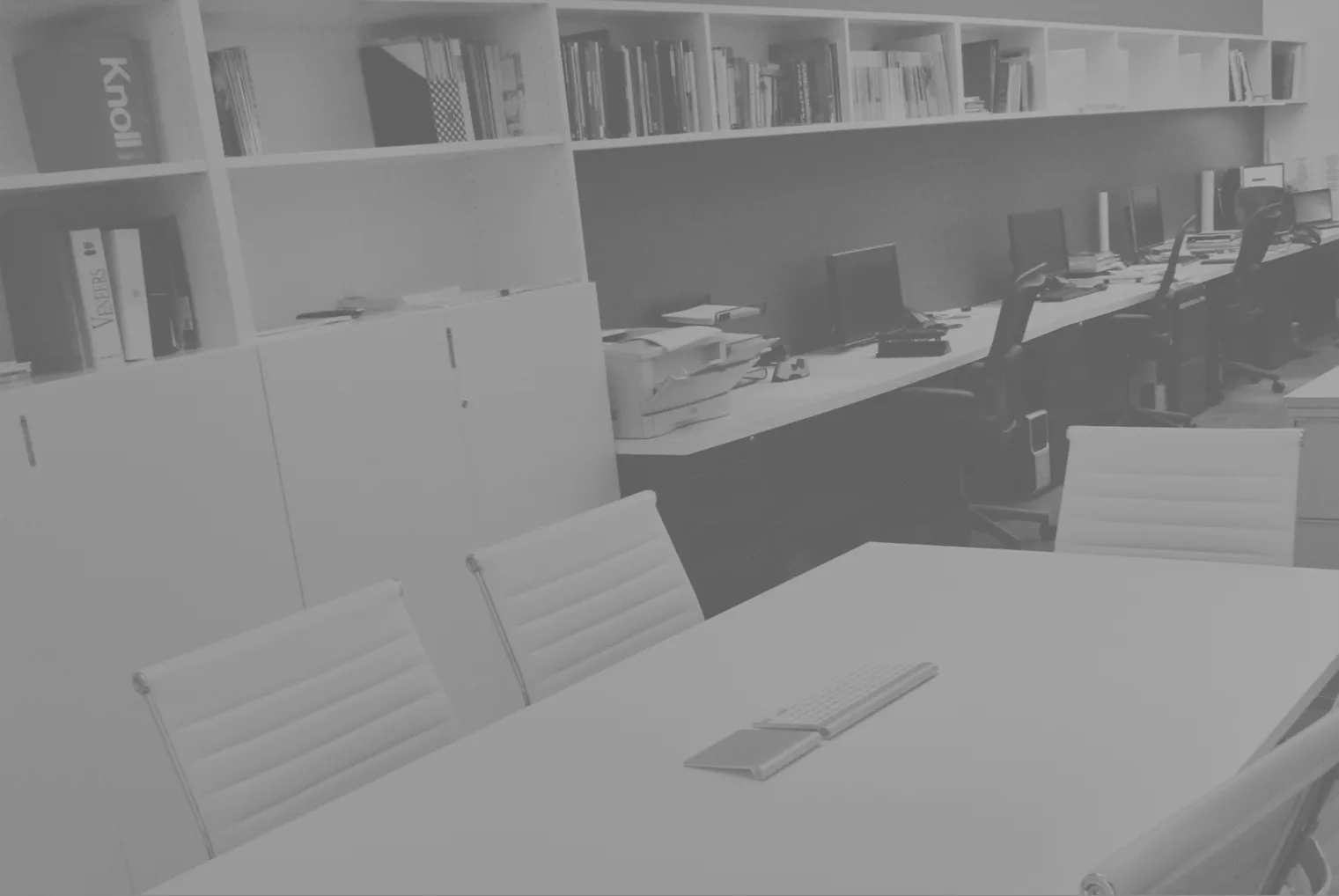 Modern office interior with white modular furniture, built-in shelving, and workstations along a dark accent wall by Ayhan Ozan.