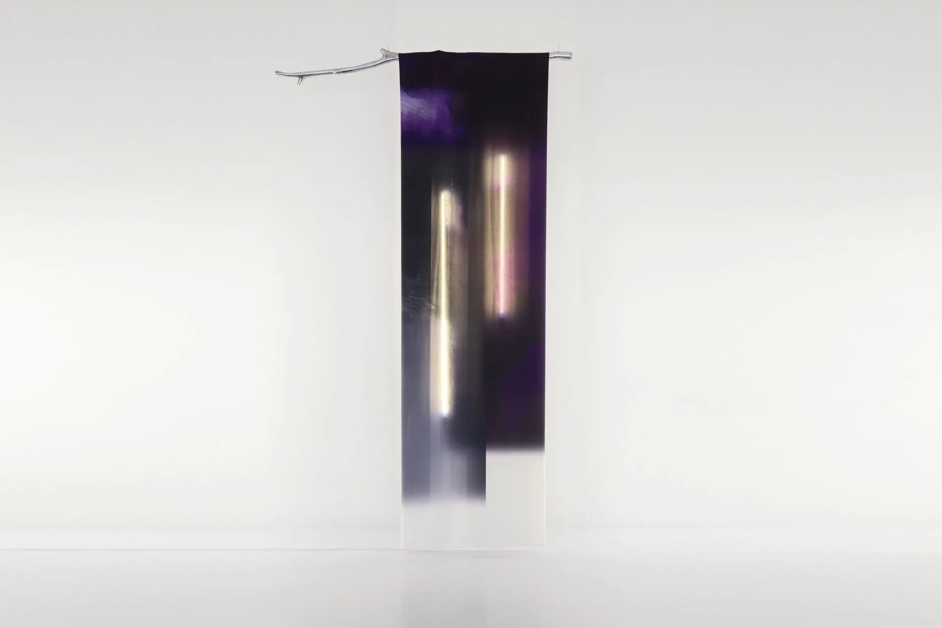 Dark fabric banner installation with illuminated vertical light elements suspended from metal rod, creating a minimalist lighting display by Batten and Kamp.