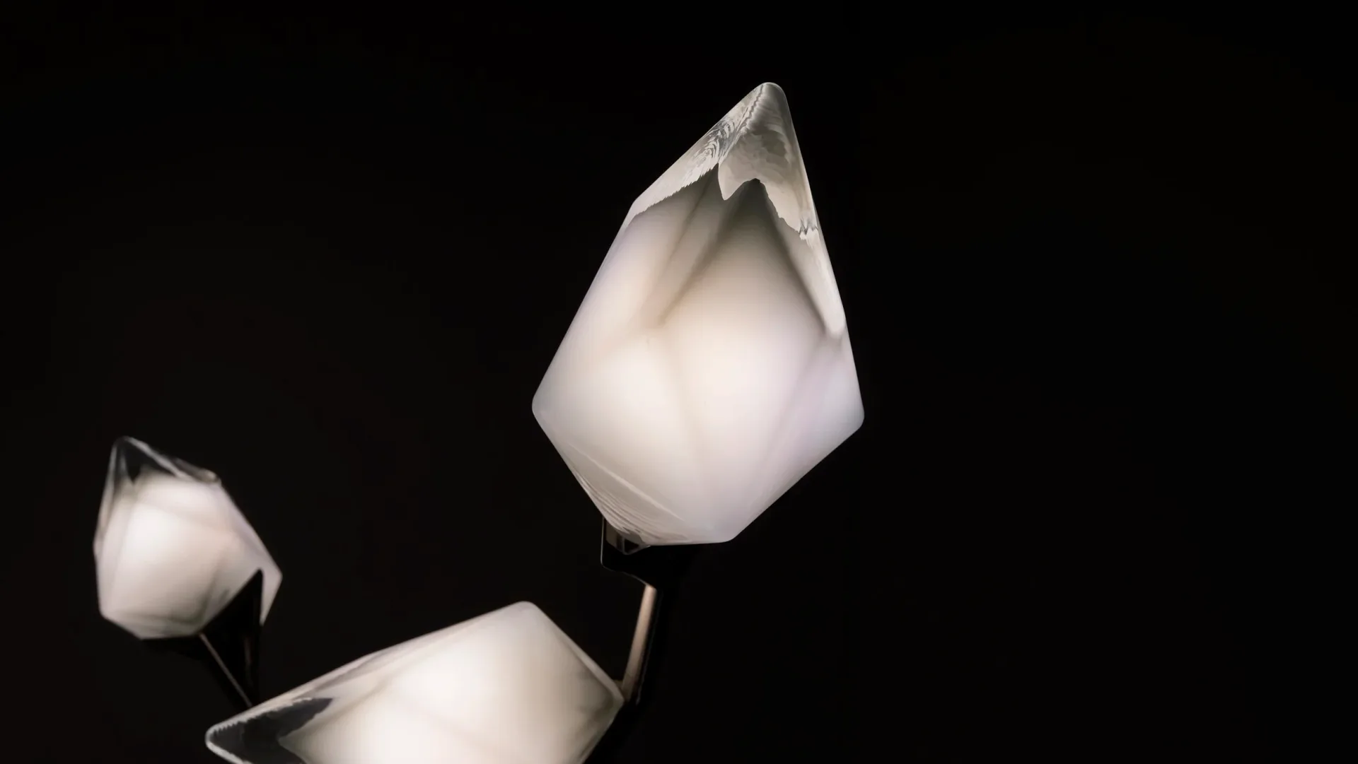 Three translucent frosted glass pendant lights with organic bulbous forms suspended against black, showcasing sculptural lighting design by Bec Brittain.
