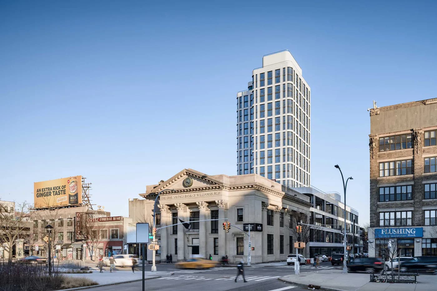 Urban streetscape featuring a classical white stone building with modern tower backdrop, clear blue sky, and surrounding brick architecture by Bella Eastham.