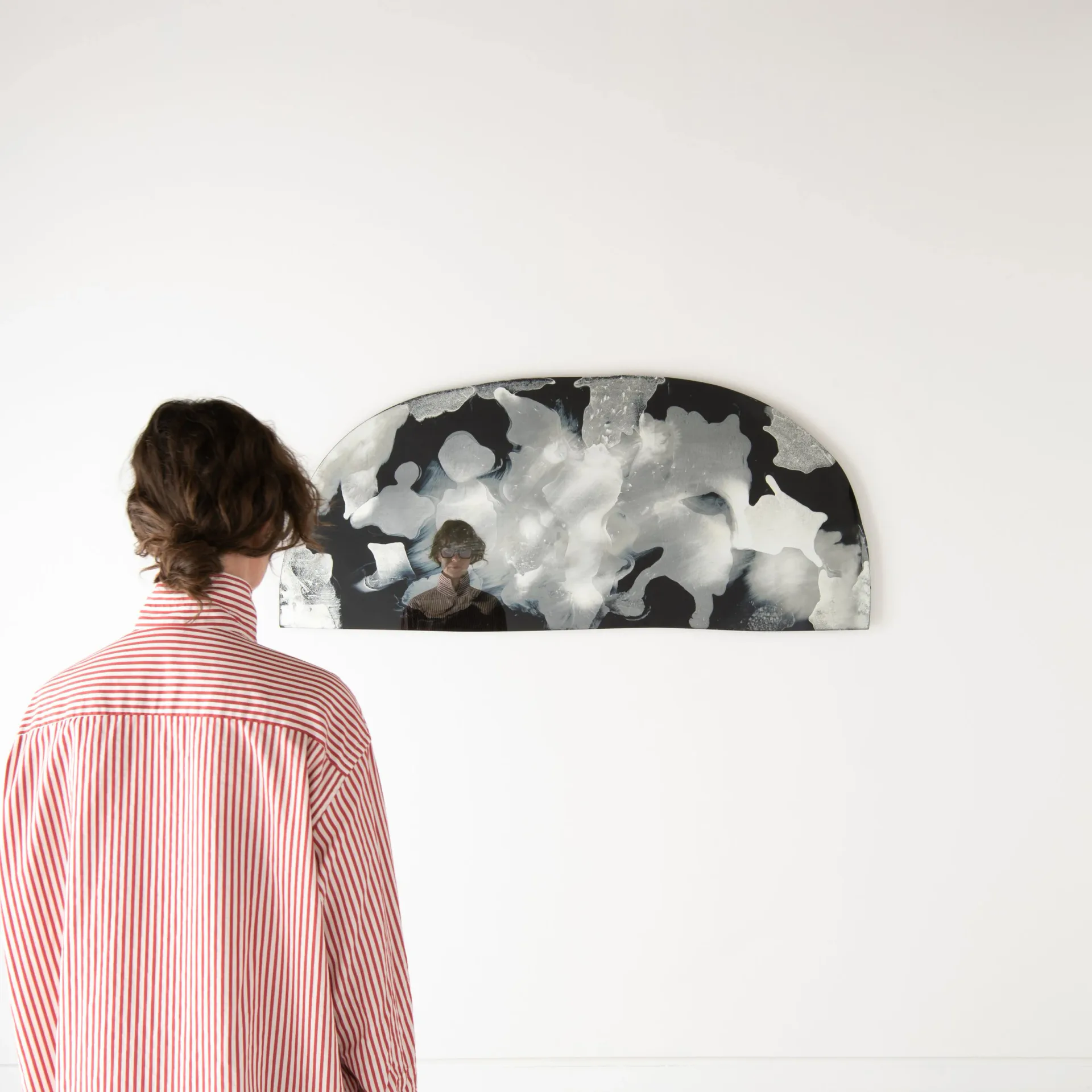 Person viewing a monochromatic wall-mounted installation featuring abstract black and white cloudy forms, by Ben & Aja Blanc.