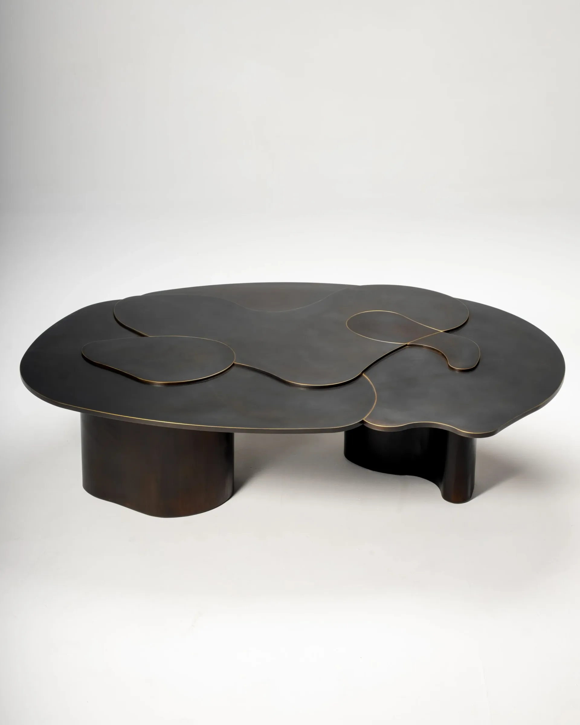 Sculptural black coffee table with undulating curved top and cylindrical base supports, photographed against white backdrop by Ben Barber.