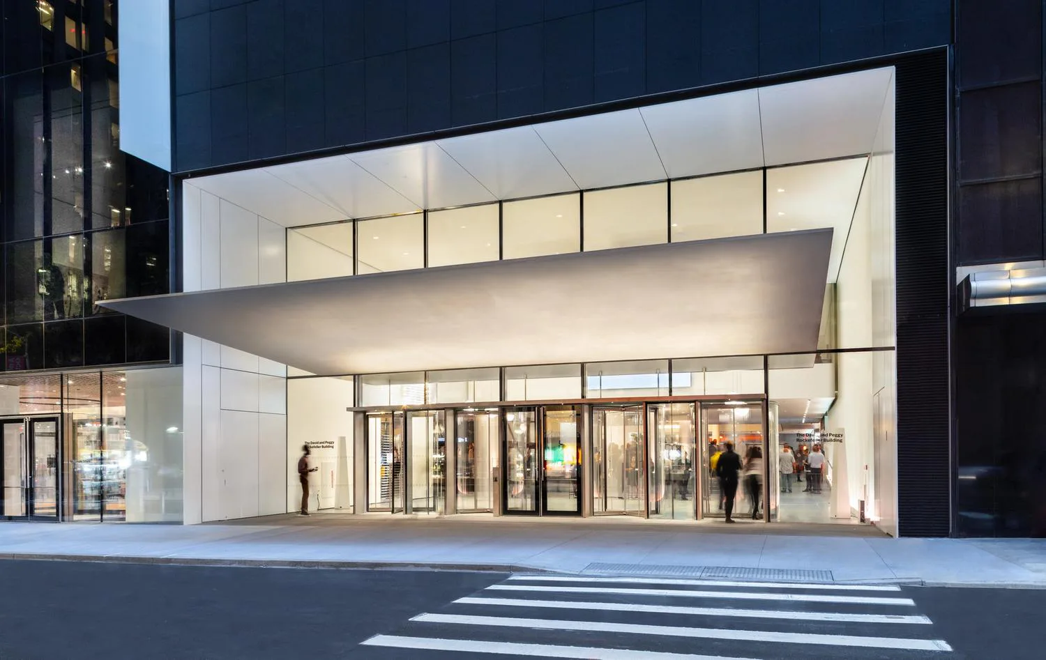 Modern storefront with illuminated white facade, clean glass entries, and minimalist design by Benjamin Gilmartin.
