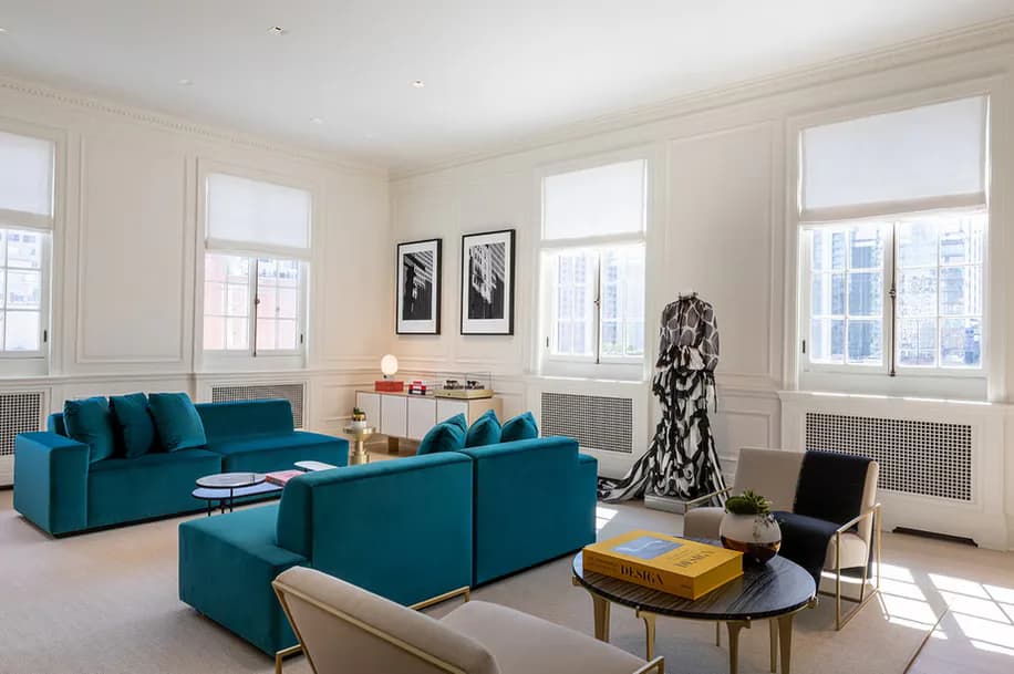 Bright contemporary living room with teal upholstered seating, large windows, cream walls, and minimalist décor by Betse Ungemack.