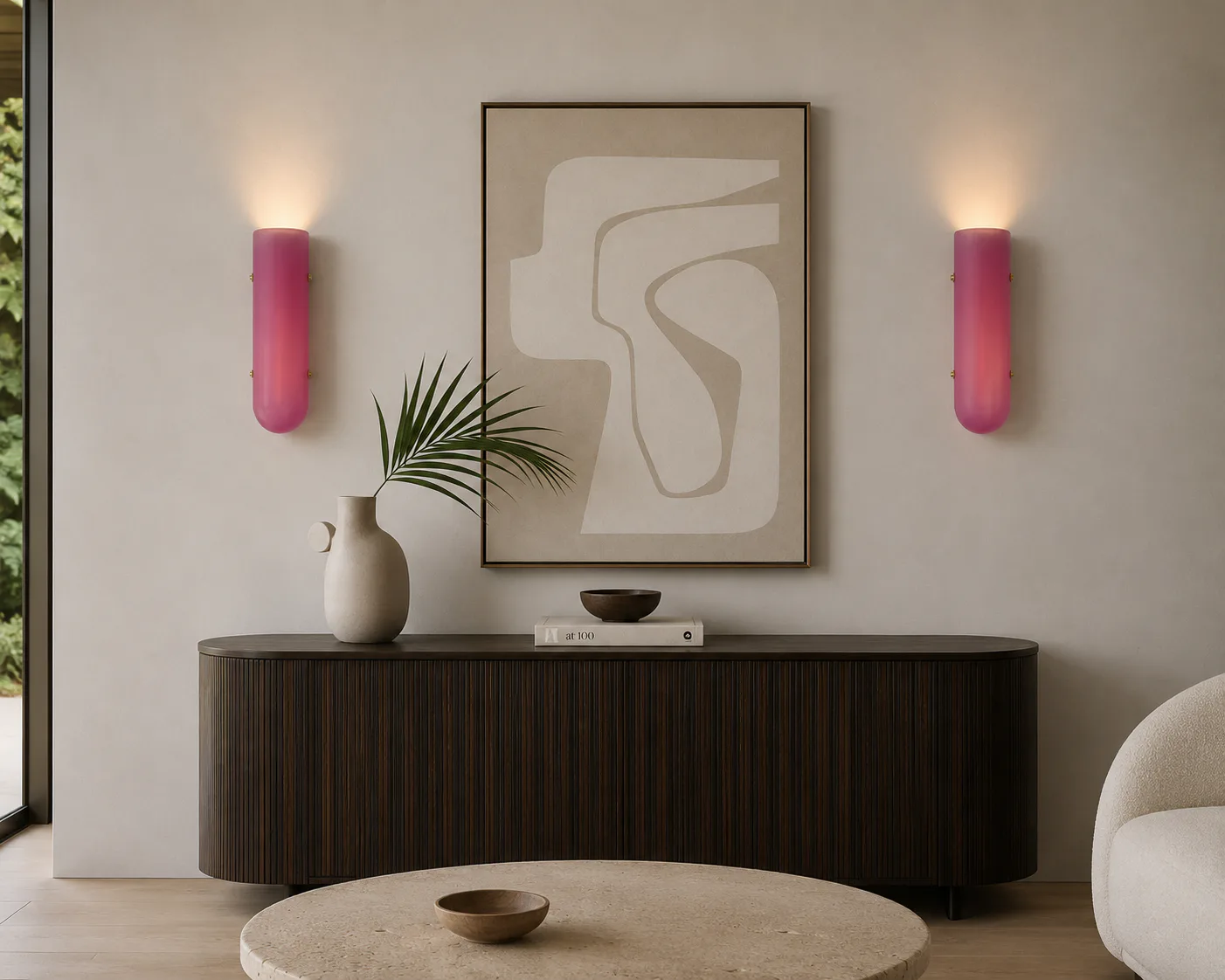 Minimalist living room with dark curved credenza, beige abstract wall art, pink cylindrical sconces, and cream round table by Bianco Light + Space.