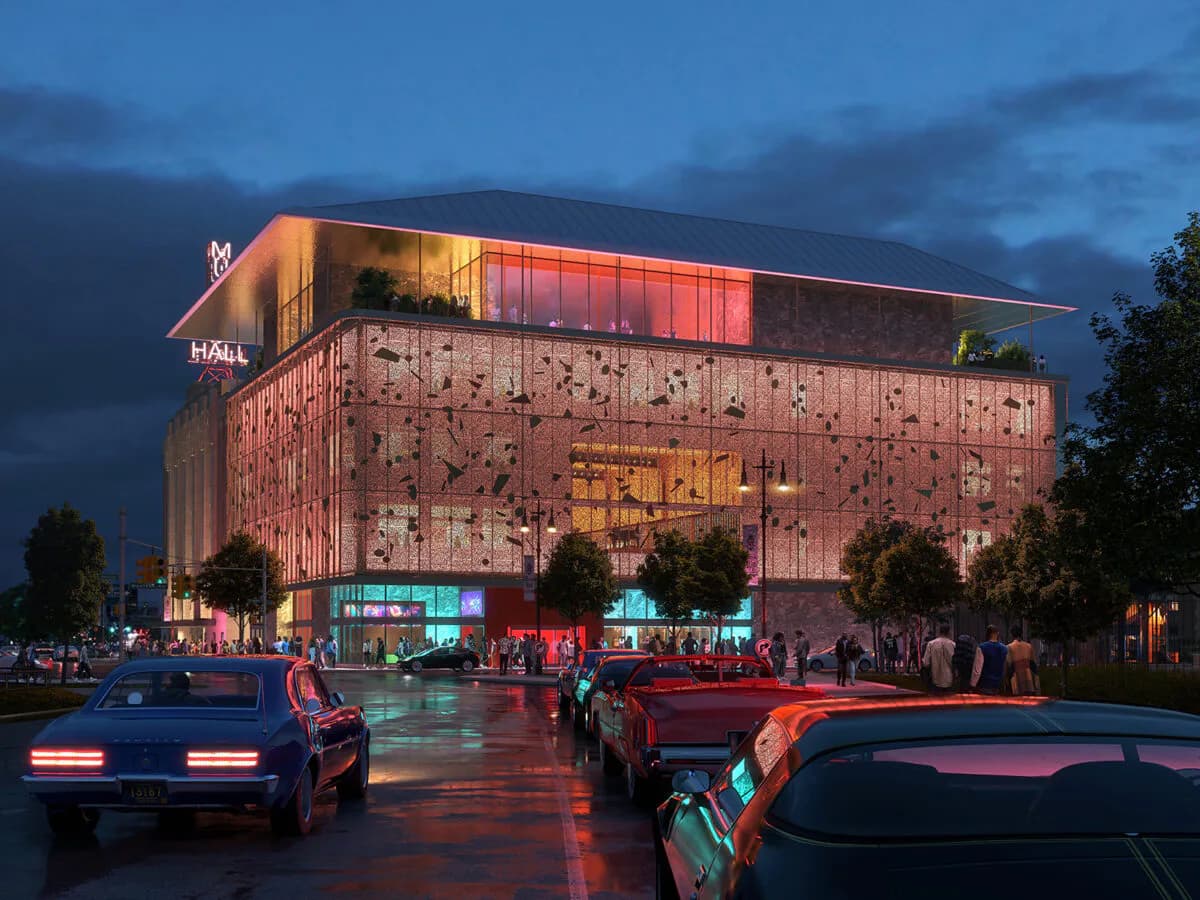 Red-brick perforated facade of an illuminated cultural building at dusk with glowing interior galleries and street-level activity by Billie Tsien.