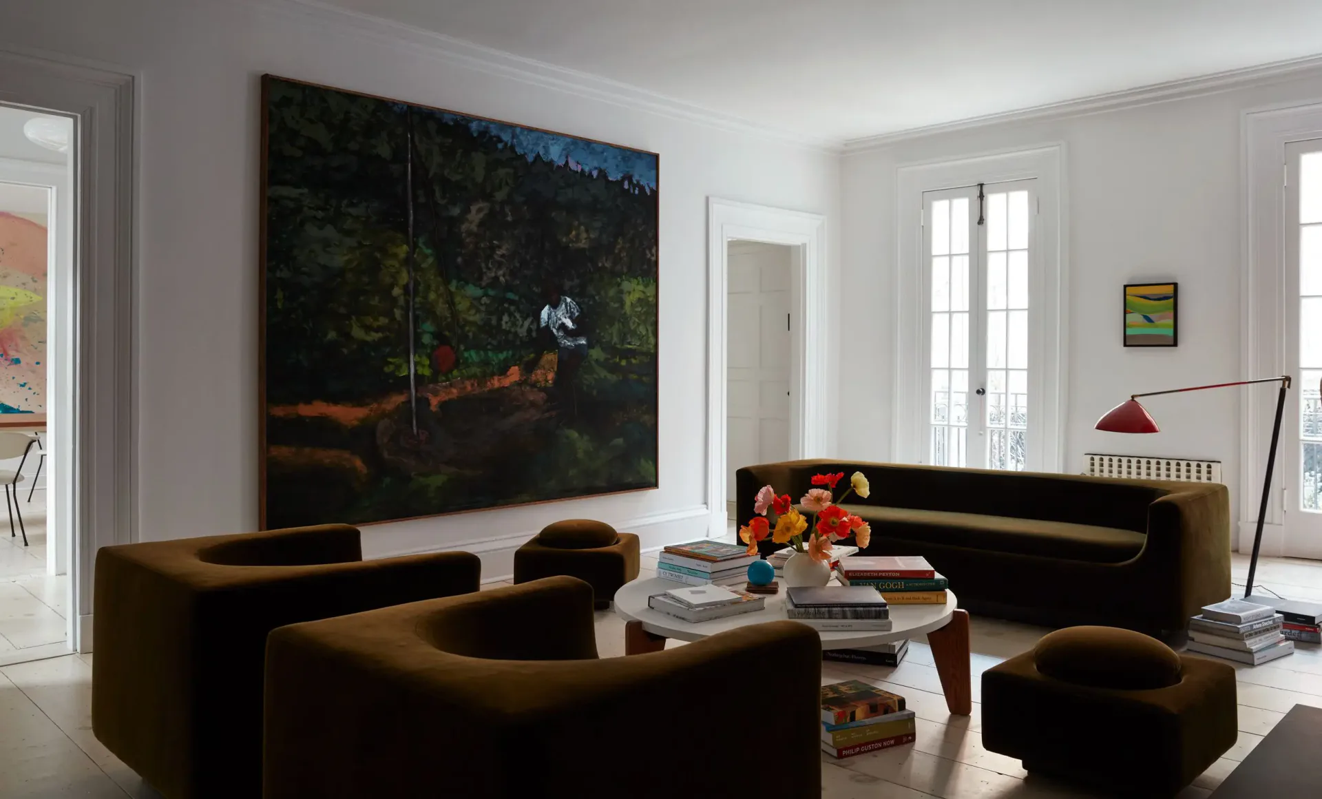 Modern living room with curved black upholstered furniture, marble coffee table, large dark landscape painting, and bright natural light from windows by Billy Cotton.