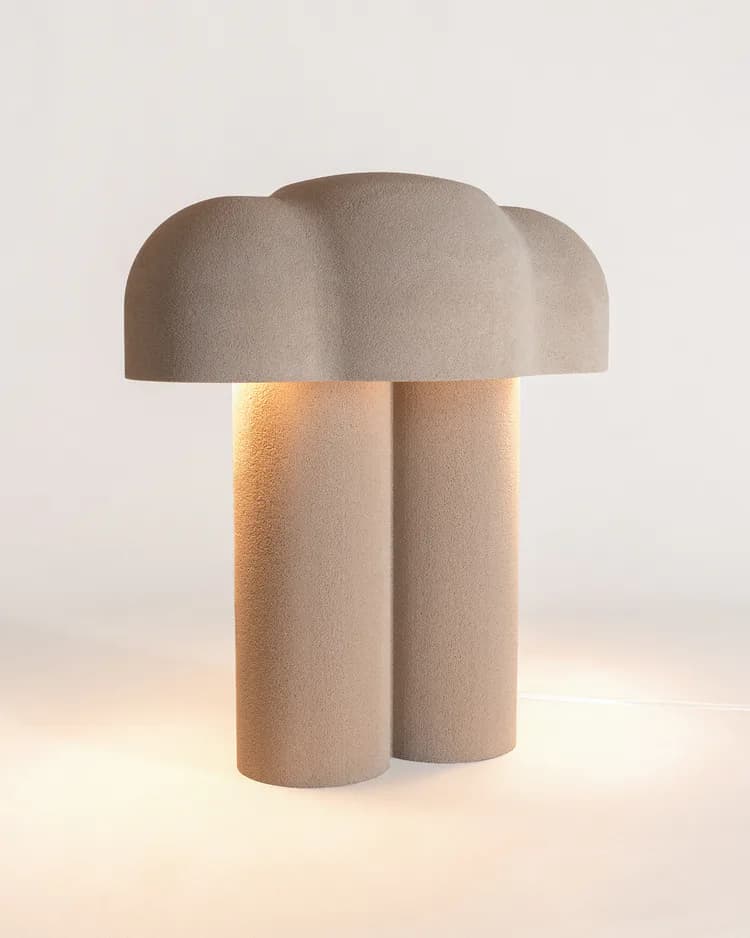 Minimalist sculptural table lamp with stacked cylindrical base and organic dome top in warm beige tones, illuminated against a soft neutral background by Blanca Codina.