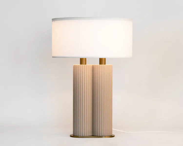 Contemporary table lamp with ribbed wood cylindrical base and warm linen shade, featuring brass accents by Blanca Codina.