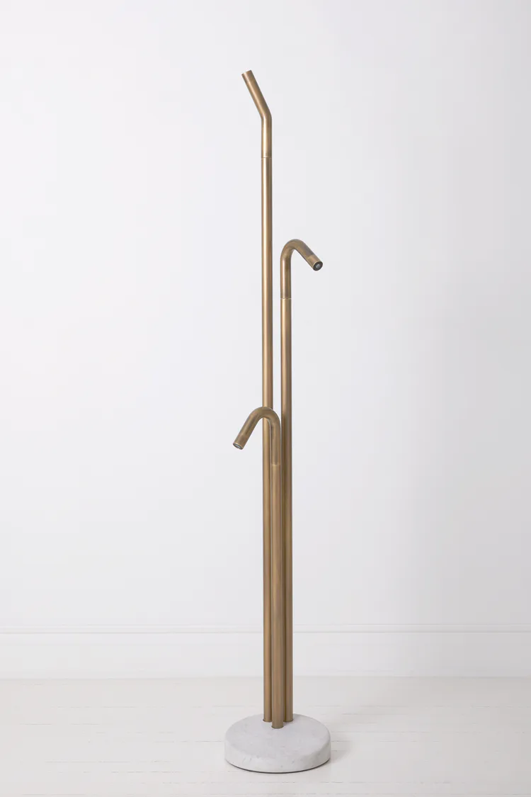 Tall bronze sculptural coat stand with curved hooks and minimalist design on white circular base by Blanca Codina.