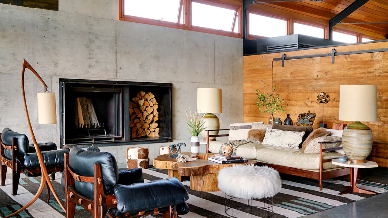 Modern living room with concrete walls, wooden ceiling, fireplace, mid-century furniture, and mixed metallics by Blue Williger.