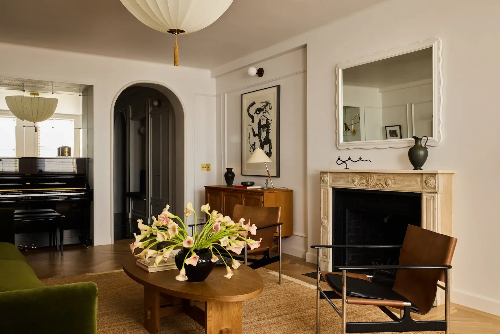 Modern living room with warm wood tones, arched doorway, fireplace, green accent chair, and contemporary furniture by Bradley Silling.