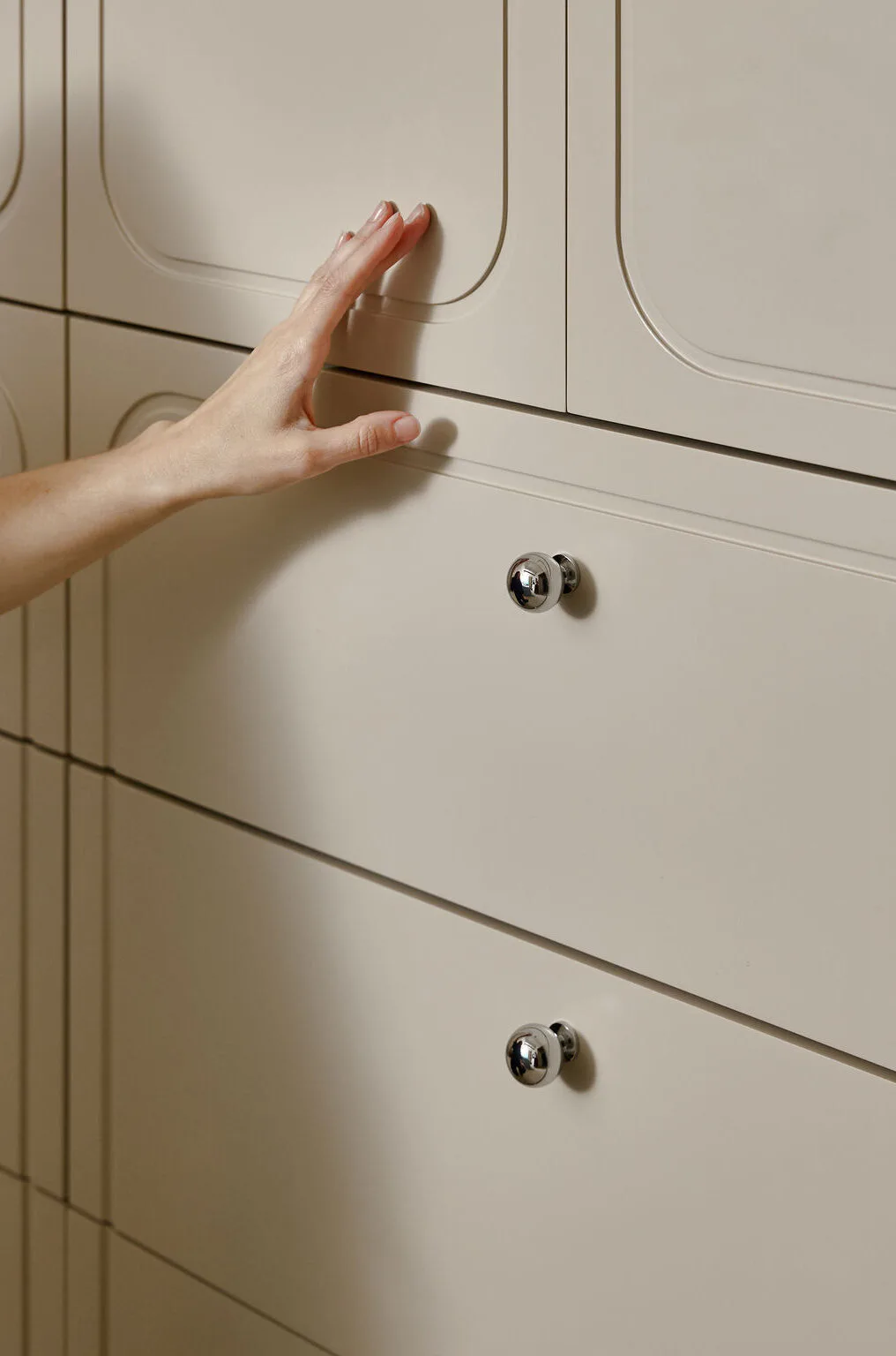 Minimalist cabinetry with curved hardware details and subtle line work in soft neutral tones by Brendan Mahoney.