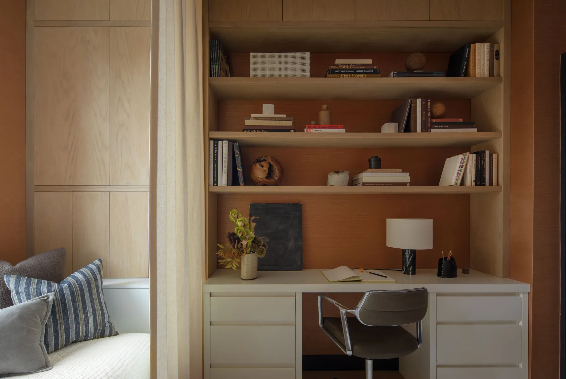 Warm wood-toned home office with built-in shelving, white desk cabinetry, and modern chair, designed by Brian Cash.