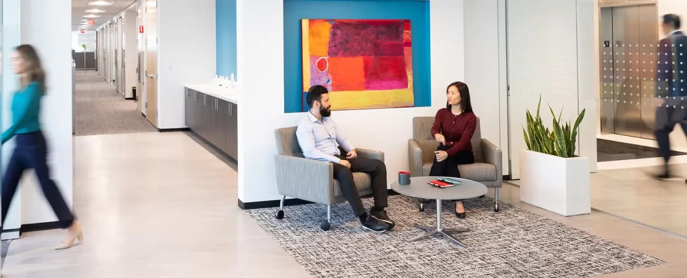 Modern office lobby with open seating area, colorful abstract artwork, potted plants, and contemporary furnishings by Brooke Horan.