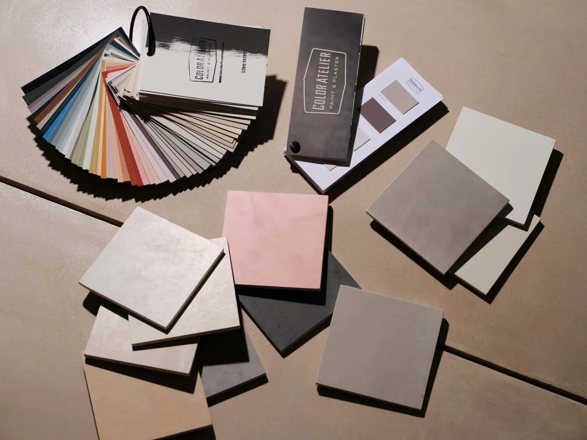 Material and color palette samples including fabric swatches, paint chips, and finishes arranged on neutral surface by Burcu K.
